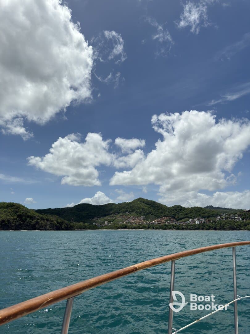 A scenic view from the bow of a boat, showcasing lush green hills and a vibrant sky, perfect for capturing the essence of a tranquil day on the water.