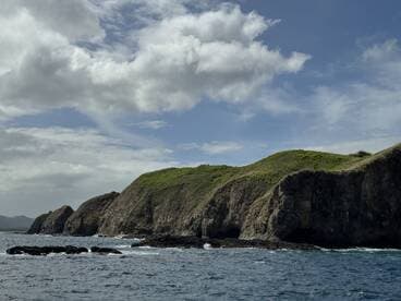 A stunning view of a rugged coastline with lush green hills under a partly cloudy sky, perfect for showcasing the natural beauty of the region.