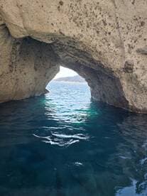 A stunning view of a natural rock arch over clear blue waters, showcasing the beauty of coastal landscapes — perfect for exploring hidden gems during boat trips.