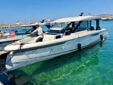 A man prepares the sleek 'Allora' boat at the dock, showcasing its stylish design against the clear waters — perfect for a day of adventure on the sea.