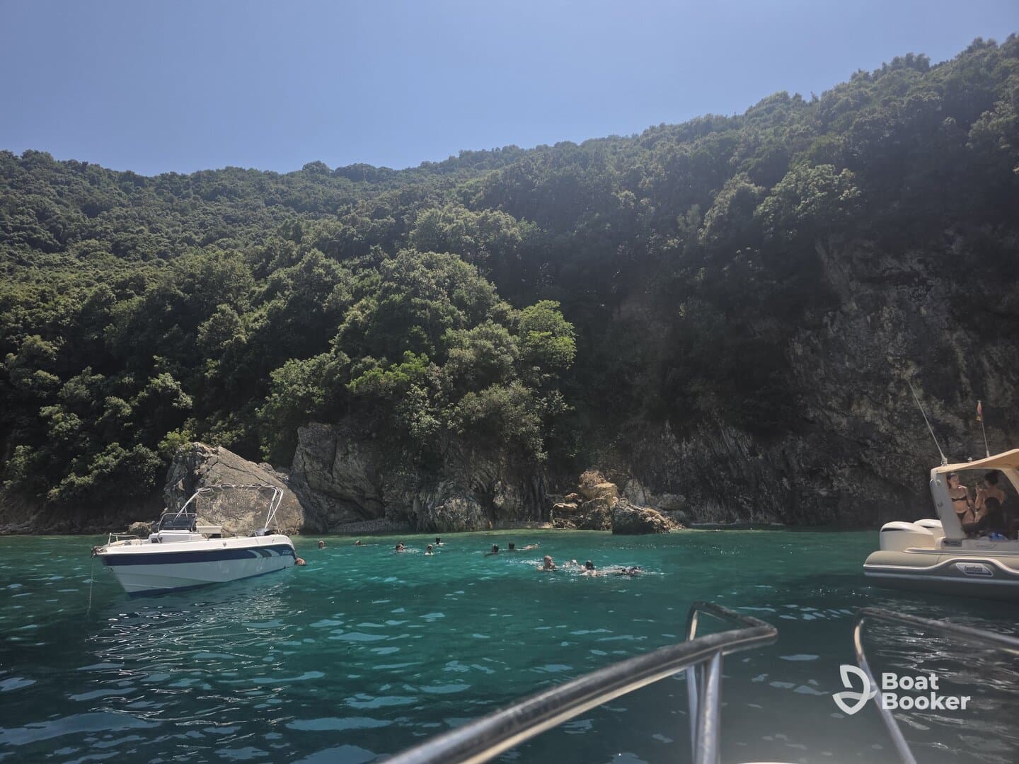 A lively scene of swimmers enjoying the clear waters near a rocky coastline, with boats anchored nearby, perfect for a day of fun and exploration.