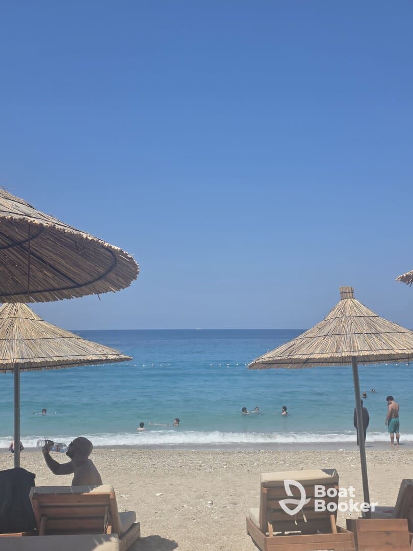 A vibrant beach scene with guests enjoying the sun and swimming in the clear waters, perfect for a relaxing day by the sea.