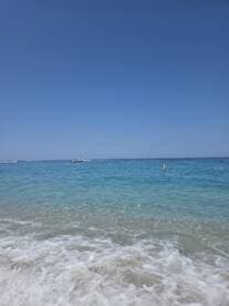 A serene view of a clear turquoise coastline with gentle waves lapping at the shore, perfect for a relaxing beach day.