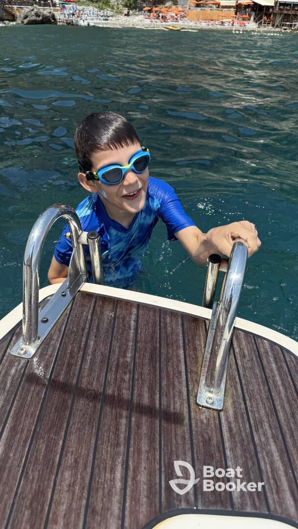 A joyful child climbs the ladder of a boat after swimming, showcasing the fun and excitement of water activities during a sunny day on the water.
