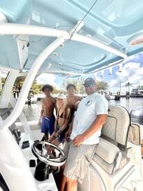 A cheerful group of young people poses on the helm of a boat, ready for a day of adventure on the water. Perfect for family outings and fun-filled excursions.