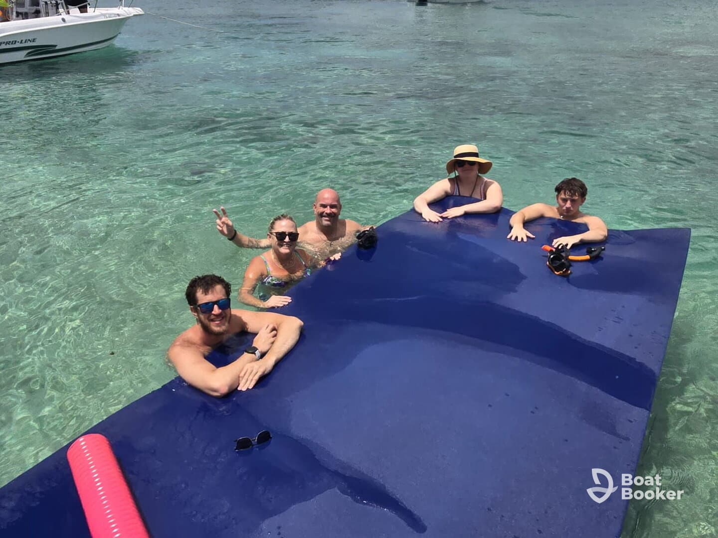 A lively group enjoys a fun day in the clear waters, relaxing on a floating mat and ready for snorkeling adventures.