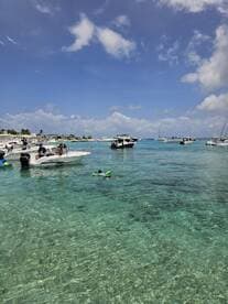 A lively scene at a popular swimming spot with boats anchored nearby, featuring a child enjoying the water with floaties — perfect for family fun and water activities.