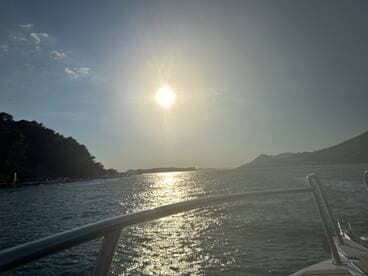 A serene view of the sun setting over the water, captured from the bow of a boat, creating a picturesque backdrop for evening cruises.