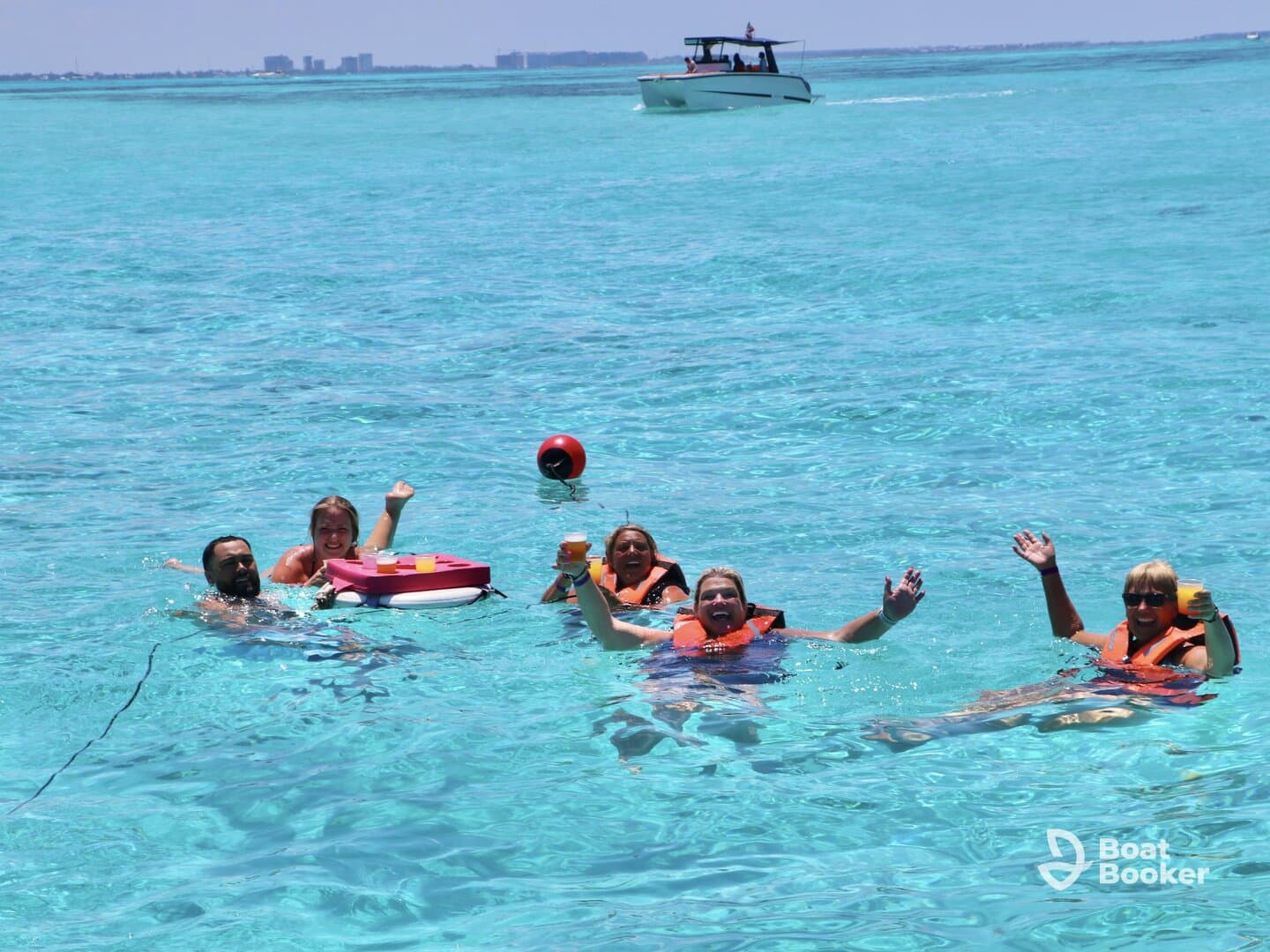 A lively group enjoys a refreshing swim in crystal-clear waters, celebrating with cocktails and laughter — the perfect backdrop for a fun day on the water.