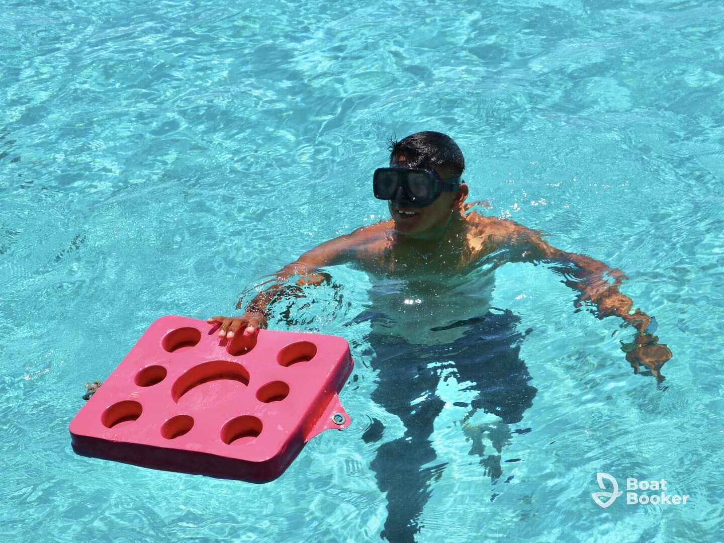 A young boy enjoys swimming with a pink float in clear blue waters, showcasing the fun of water activities and snorkeling adventures.