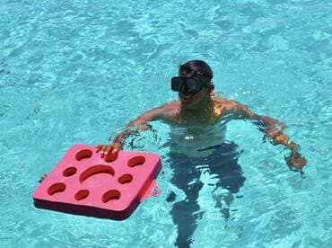 A young boy enjoys swimming with a pink float in clear blue waters, showcasing the fun of water activities and snorkeling adventures.