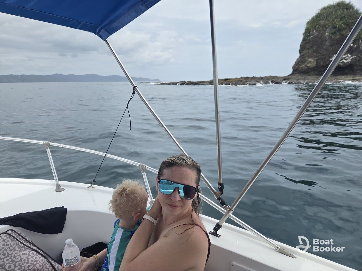 A mother enjoys a scenic boat ride with her child, capturing a moment of family bonding on the water amidst beautiful coastal views.