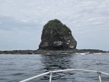 A scenic view of a rocky formation emerging from the ocean, captured from a boat — perfect for showcasing the natural beauty of coastal landscapes.