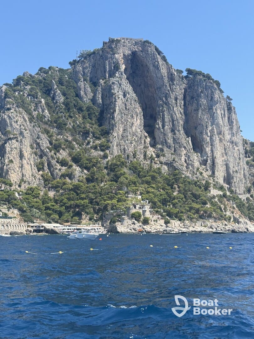 A stunning view of rocky cliffs and lush greenery along the coastline, showcasing the natural beauty of the island — perfect for scenic boat tours.