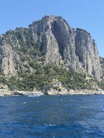 A stunning view of rocky cliffs and lush greenery along the coastline, showcasing the natural beauty of the island — perfect for scenic boat tours.