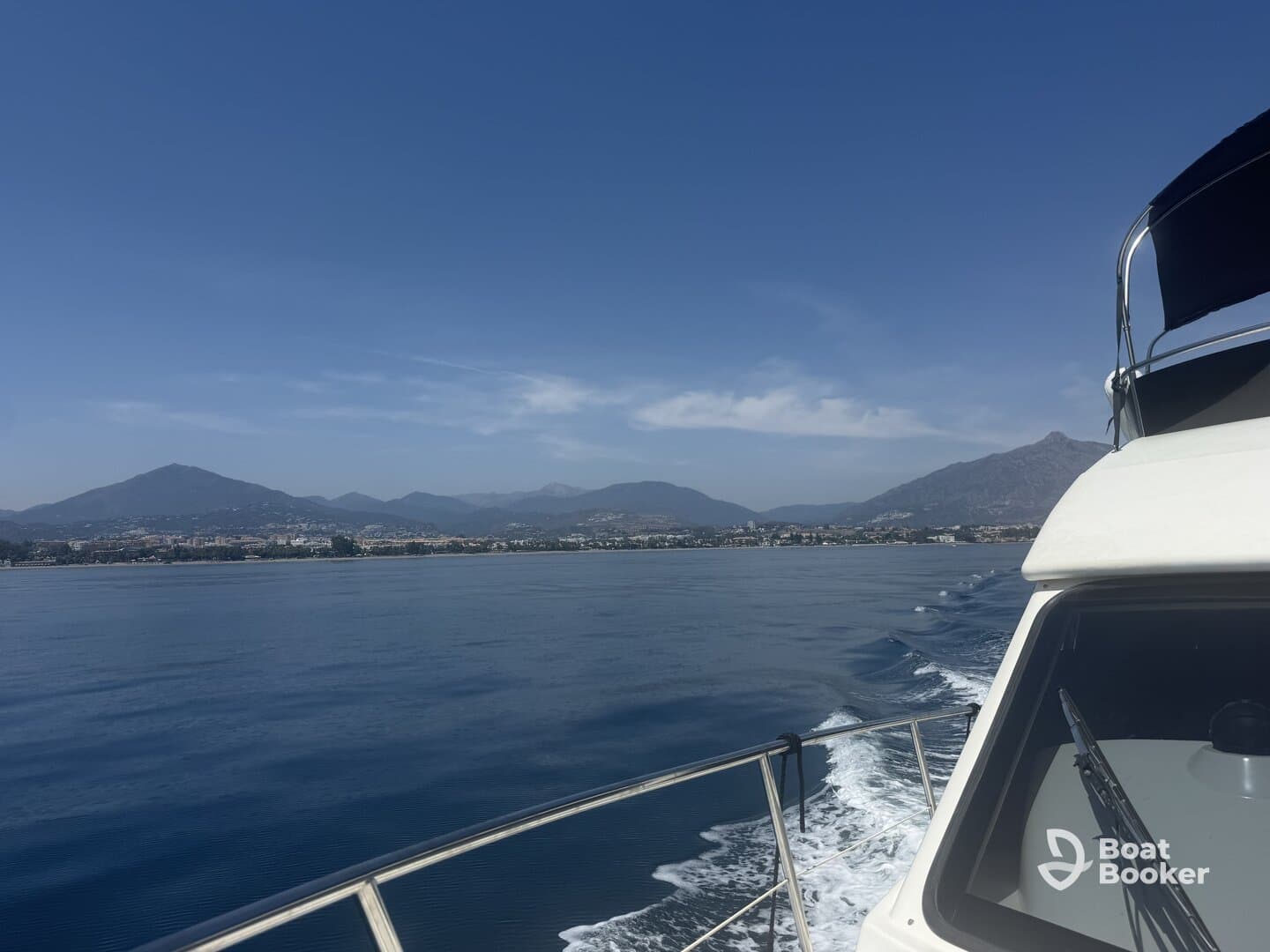 A scenic view of a boat cruising through calm waters with mountains in the background, showcasing the beauty of the coastline.
