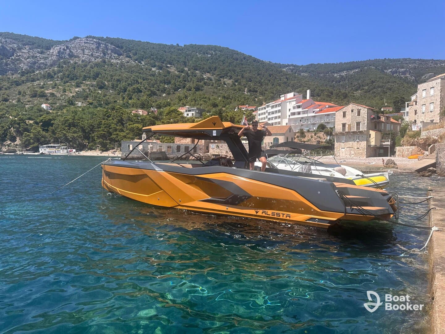 A vibrant boat is docked in clear waters with a person celebrating on deck, showcasing the perfect setting for a fun day on the water.