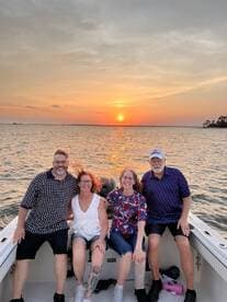 A cheerful group of friends enjoys a sunset cruise on a boat, capturing a perfect moment of camaraderie and scenic beauty.