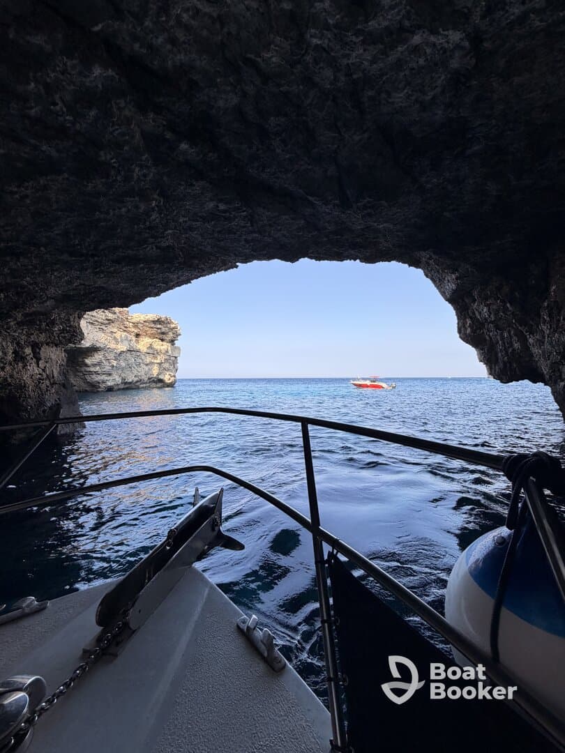 A scenic view from inside a cave, showcasing the tranquil waters and a distant boat outside — perfect for exploring coastal wonders.