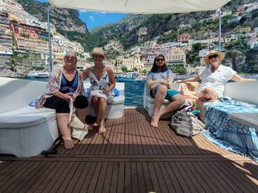 A cheerful group of friends relaxes on a boat, enjoying the stunning coastal views of Positano — perfect for a memorable day on the water.