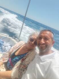 A joyful couple smiles for a selfie while enjoying a boat ride on the ocean, capturing a moment of happiness and adventure on the water.