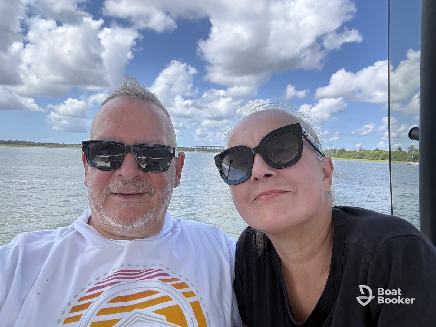 A cheerful couple enjoys a sunny day on the water, capturing a memorable moment aboard their boat. Perfect for showcasing romantic getaways or fun outings.