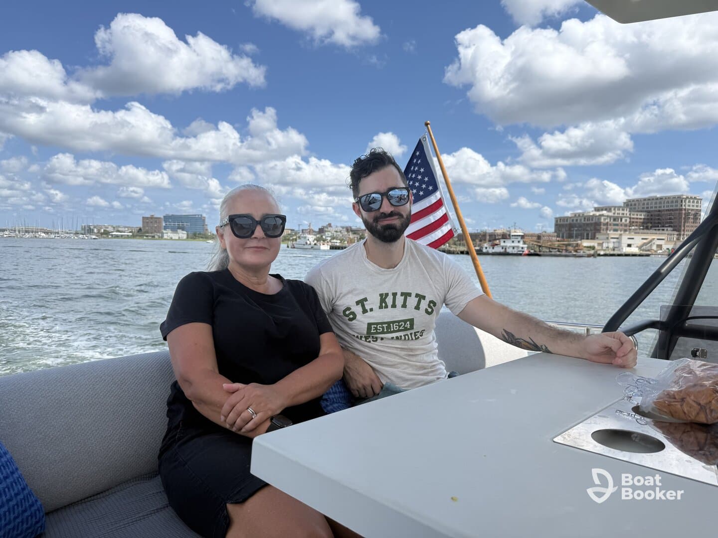 A couple enjoys a relaxing moment aboard a boat, with scenic views of the waterfront and a clear blue sky in the background.