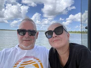 A cheerful couple enjoys a sunny day on the water, capturing a memorable moment aboard their boat. Perfect for showcasing romantic getaways or fun outings.