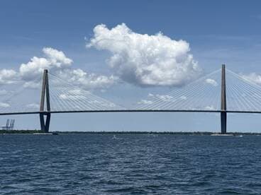 A scenic view of a bridge spanning over water, framed by a backdrop of clouds, showcasing the beauty of the landscape.