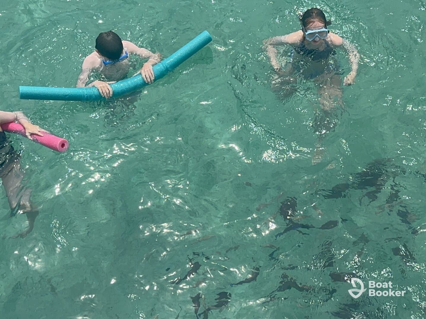 Two children enjoy a fun day in the clear waters, playing with pool noodles — a perfect family-friendly activity for summer adventures.
