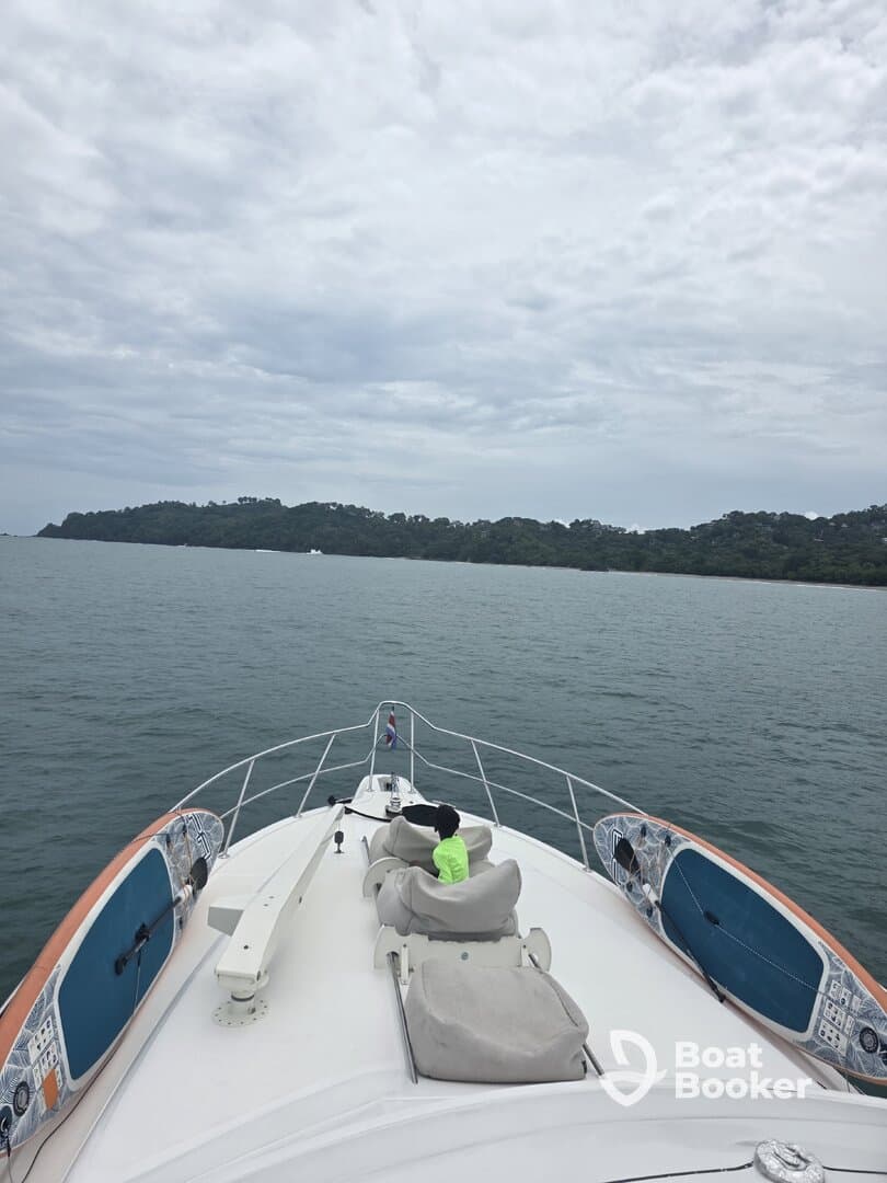 A child enjoys the view from the front of a boat, with a paddleboard visible alongside — a perfect moment for family adventures on the water.