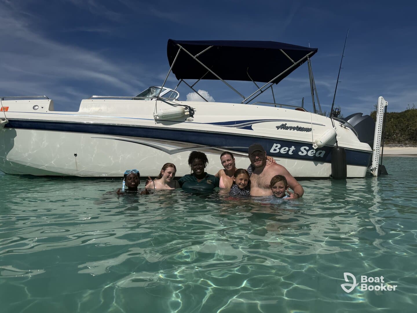 A joyful family enjoys a fun day swimming in crystal-clear waters next to their boat, 'Bet Sea' — perfect for memorable sandbar stops and family adventures.