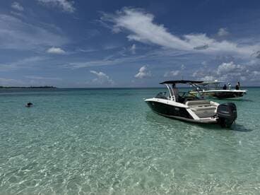 A swimmer enjoys the clear turquoise waters while boats are anchored nearby, creating a perfect setting for a day of snorkeling and relaxation.
