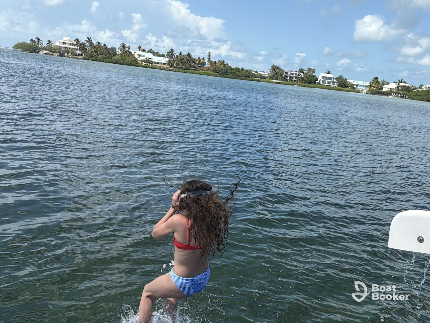A young girl joyfully jumps into the water, capturing the essence of fun and adventure on a sunny day. Perfect for showcasing family-friendly water activities.