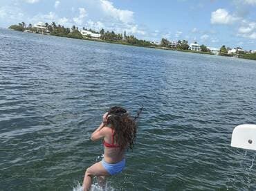 A young girl joyfully jumps into the water, capturing the essence of fun and adventure on a sunny day. Perfect for showcasing family-friendly water activities.