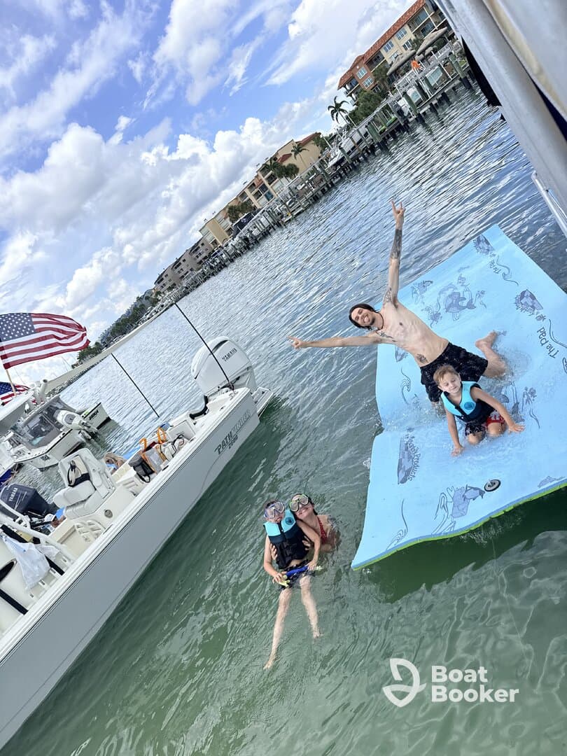 A joyful family enjoys a fun day in the water, with kids playing on a floating mat and adults swimming nearby — perfect for memorable summer outings.