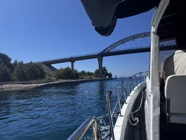 A scenic view from a boat navigating under a bridge, showcasing the beautiful waterways and lush greenery — perfect for exploring coastal landscapes.
