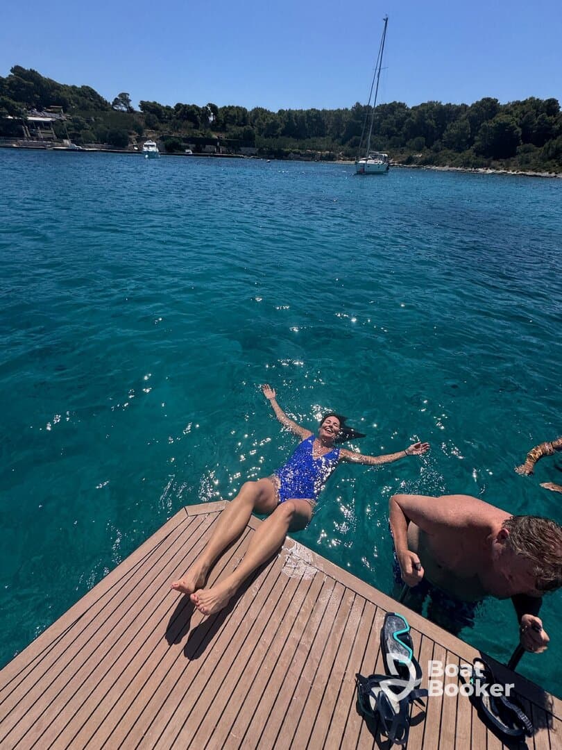 A joyful scene of guests enjoying a sunny day by the water, with one woman floating on the dock and others nearby, perfect for summer adventures and relaxation.