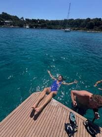 A joyful scene of guests enjoying a sunny day by the water, with one woman floating on the dock and others nearby, perfect for summer adventures and relaxation.