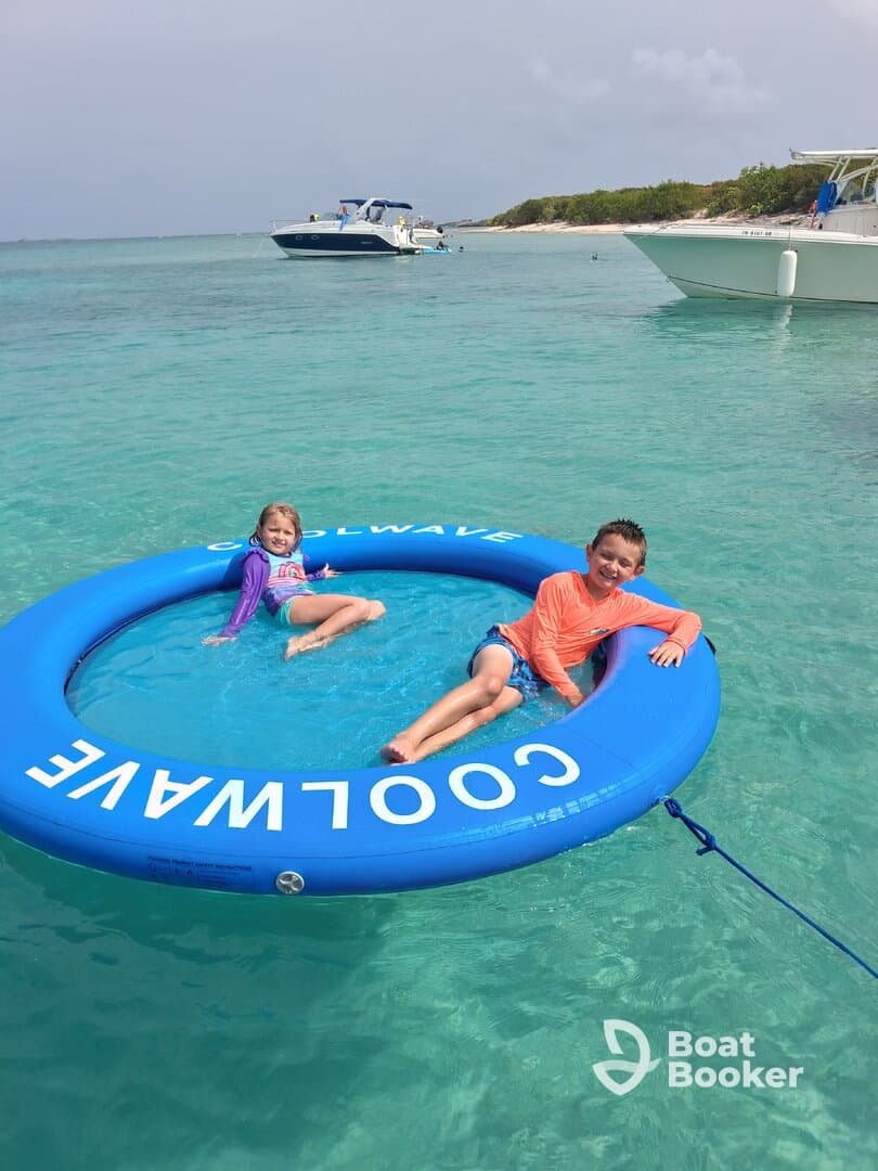 Two children enjoy a fun day on a floating mat in crystal-clear waters, perfect for family adventures and beach outings.