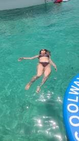 A woman floats serenely in crystal-clear waters, enjoying a perfect day of relaxation and fun in the sun — an ideal scene for summer adventures.