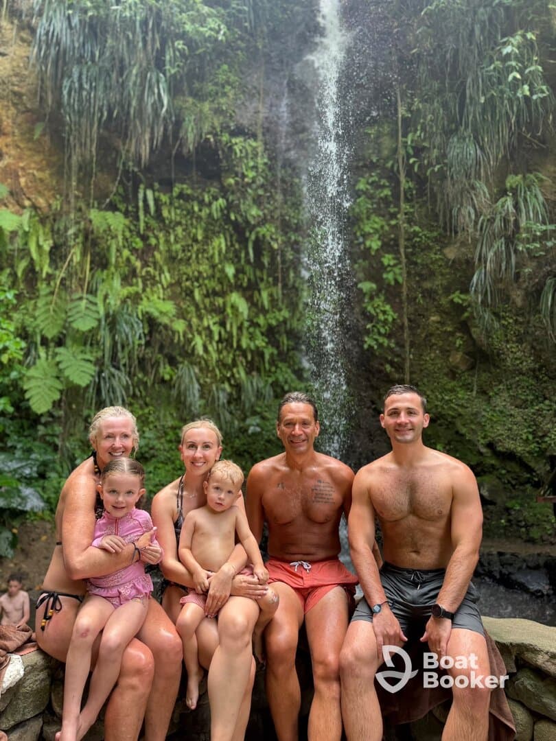 A joyful family poses together at a stunning waterfall, capturing a memorable moment of fun and adventure in nature.