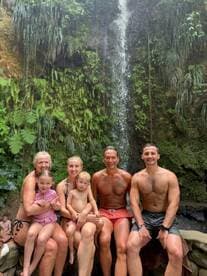 A joyful family poses together at a stunning waterfall, capturing a memorable moment of fun and adventure in nature.