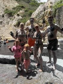 A joyful family enjoys a mud bath experience, showcasing their playful side while covered in mud — a fun and memorable activity during their adventure.