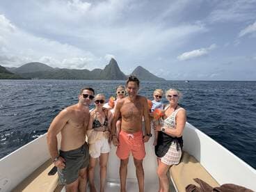 A joyful group poses on a boat with stunning island scenery in the background, perfect for family adventures and memorable outings on the water.