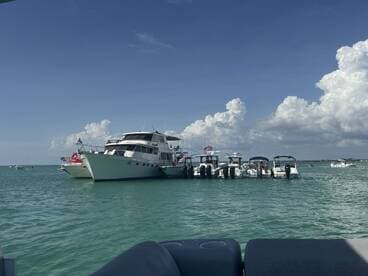 A variety of boats anchored together in clear waters under a bright sky, showcasing a lively day on the water.