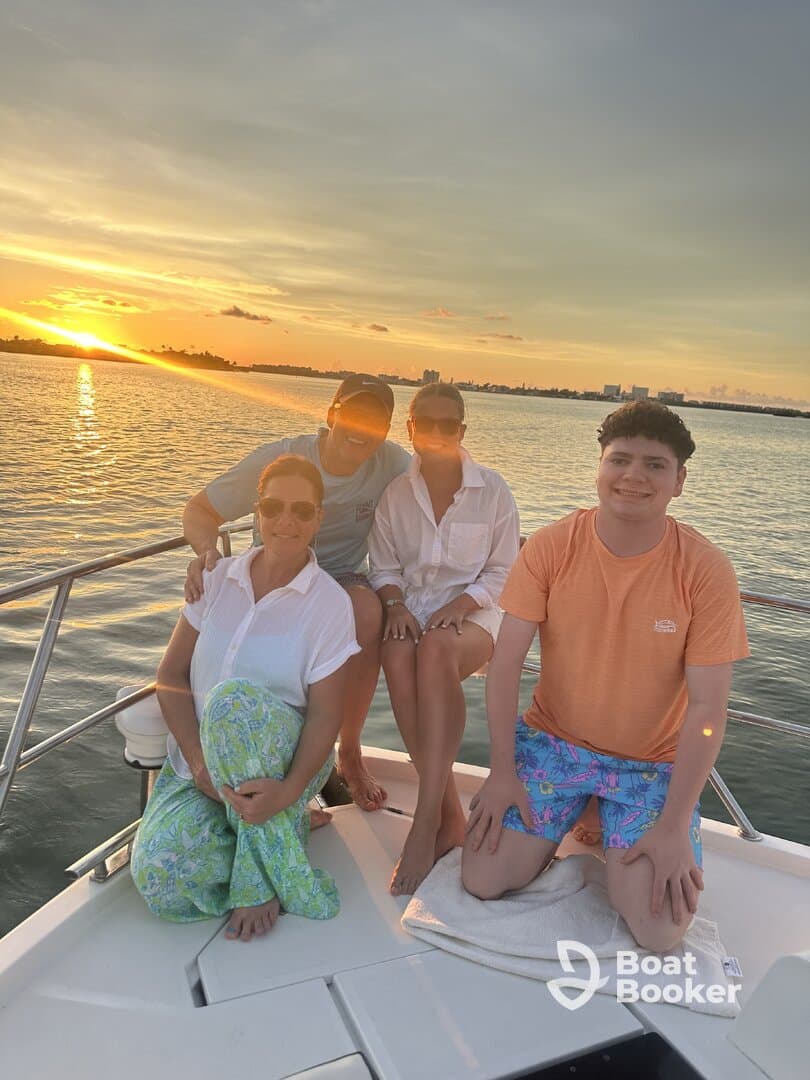 A joyful family poses together on a boat at sunset, capturing a perfect moment of togetherness and celebration on the water.