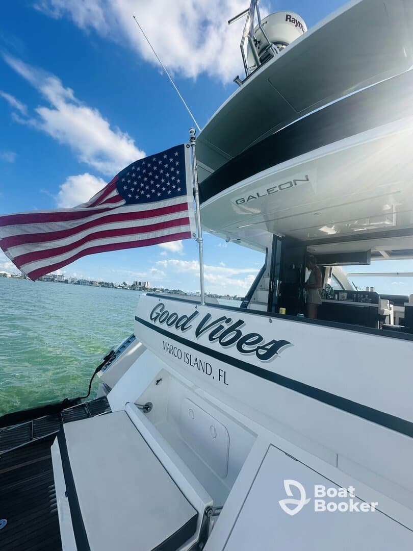 A stunning view of the 'Good Vibes' yacht featuring an American flag, showcasing the sleek design and inviting atmosphere of boating in Marco Island, FL.