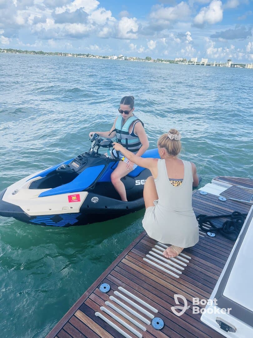 Two women prepare for an exciting jet ski ride on the water, showcasing the thrill of water sports and adventure on a sunny day.
