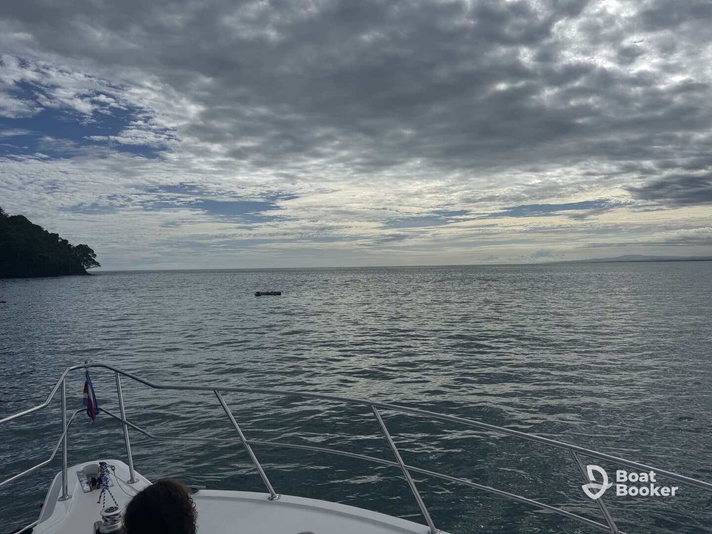 A serene view of the ocean with dramatic clouds, captured from the bow of a boat, showcasing the tranquil beauty of a day on the water.